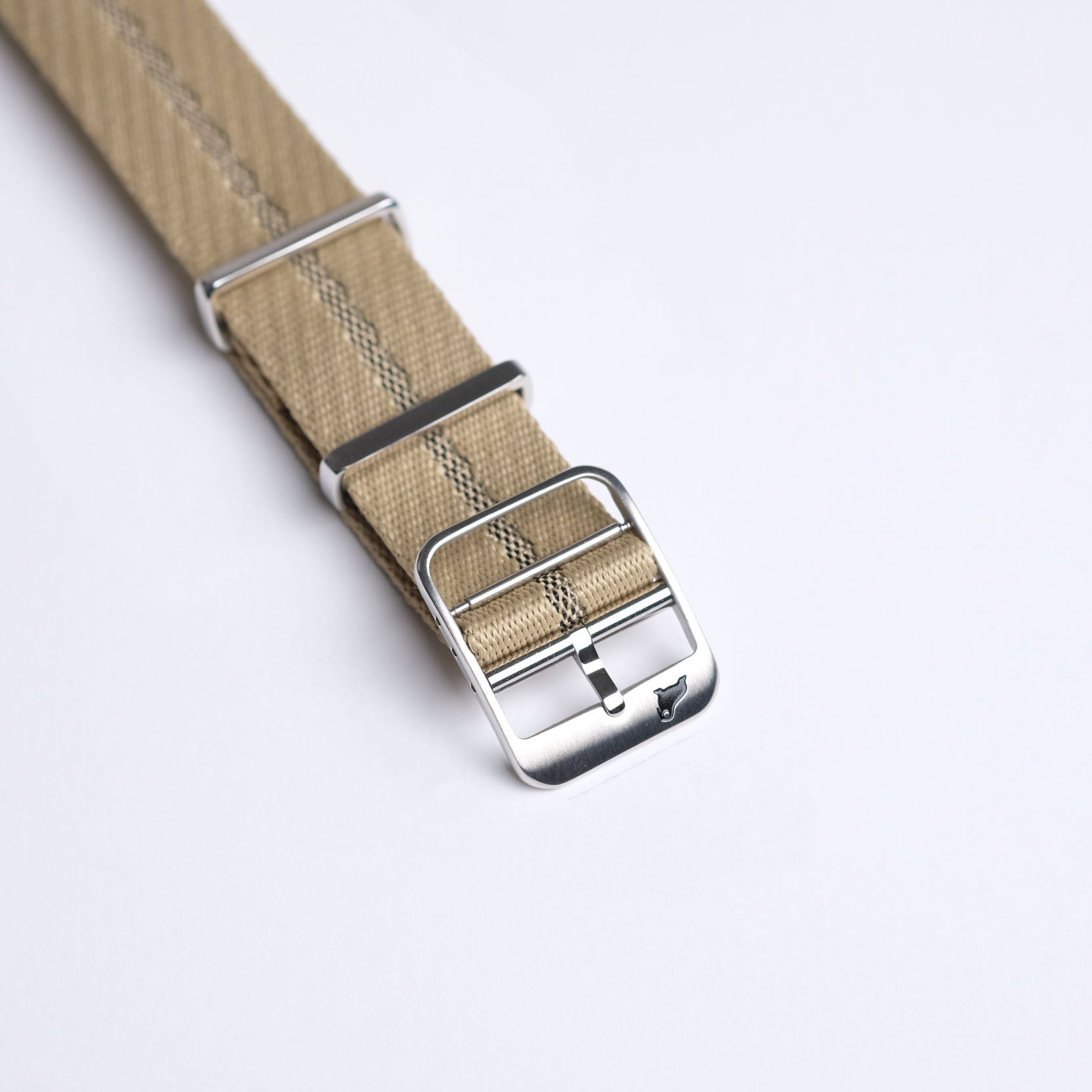 Close-up of the Engraved Stripe watch strap in Beige Brown Green with jacquard weave, silver buckle, and adjustable nylon, laid diagonally.