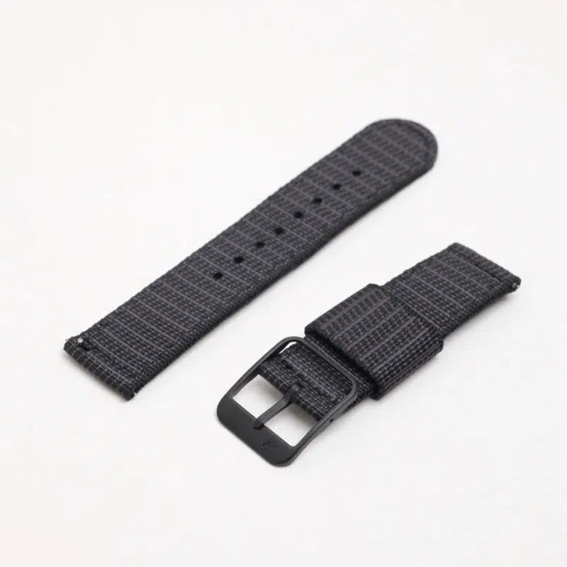 The X-Hatch Watch Strap in black polyester with a textured pattern, quick-release spring bars, buckle clasp, and adjustment holes on a white background.