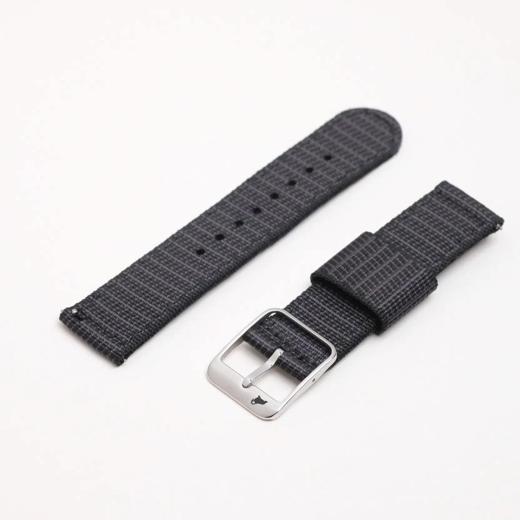 Two X-Hatch Watch Straps in Black, featuring dark gray textured polyester. One with a silver buckle and anchor, the other with adjustment holes.