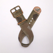 The RSM Camo Strap features a distressed copper buckle and textured camouflage design, casually looped on a white background to highlight its rugged style.