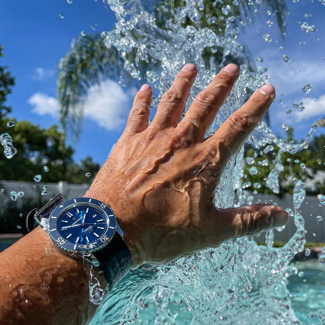 Hand flipping a blue diver watch on an RSM Engraved Stripe Series strap, a washable NATO band perfect for water sports.