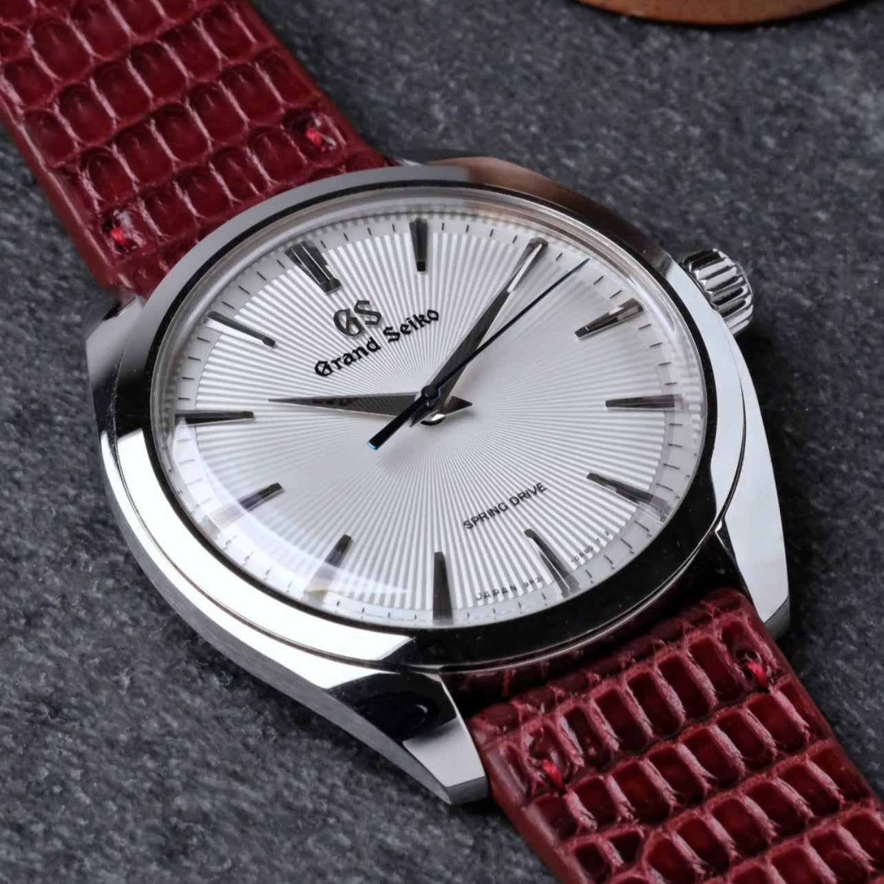 Burgundy red lizard watch strap from RSM Watch strap is placed on the Grand Seiko SBGY limited edition with white fluted dial. The burdundy lizard has vertical pattern has different tones of red and burgundy from the process of the dying methods.