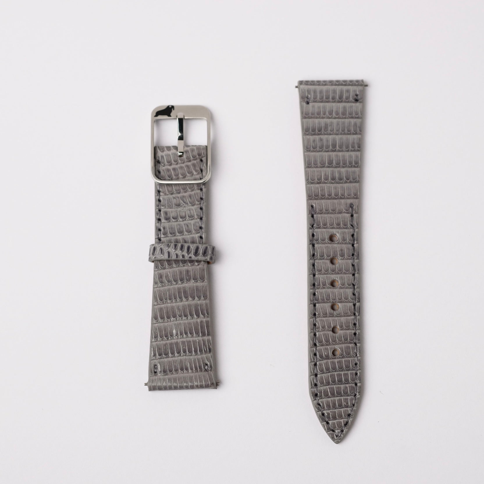 A set of a gray Spanish lizard vertical pattern RSM Watch Strap are displayed on a white background. The left features a 316L stainless steel  buckle, while the right has a pointed end. Both exhibit an elegant and beautiful grey shaded design for your timepiece.