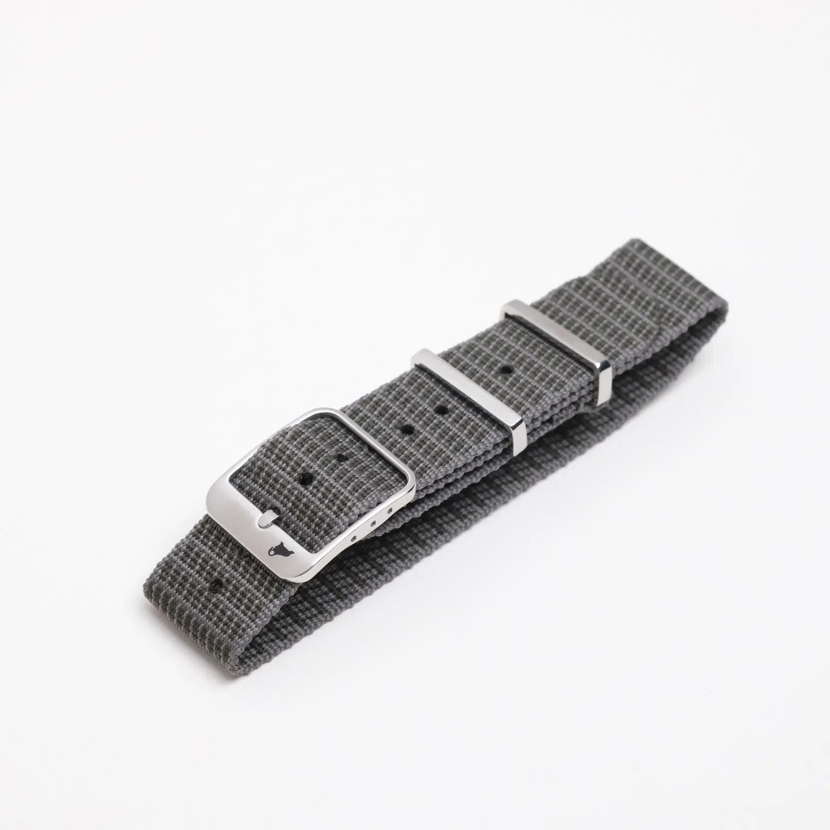 The Single Pass X-Hatch Watch Strap by RSM features durable, textured gray fabric with a silver buckle and two metal adjustment loops, displayed on a white surface.