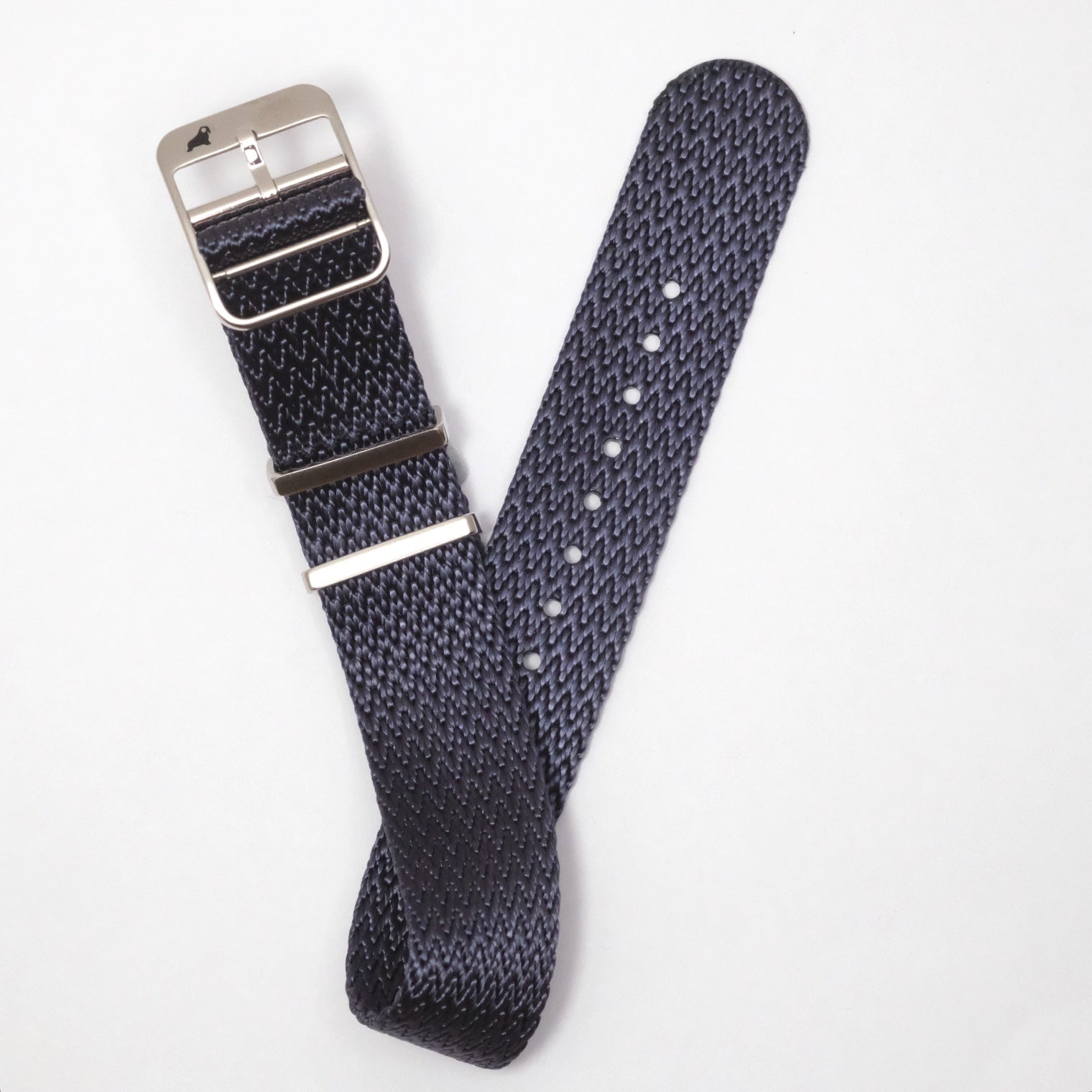 The Herringbone Twill in Icarus Blue by RSM Watch Strap features a textured NATO design with a silver buckle and adjustable strap, partially looped on a white background.