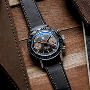 Nivada Grenchen Chronomaster with brown sub-dials, paired with RSM Raven Black Buttero strap, beige stitches, resting on timber background.