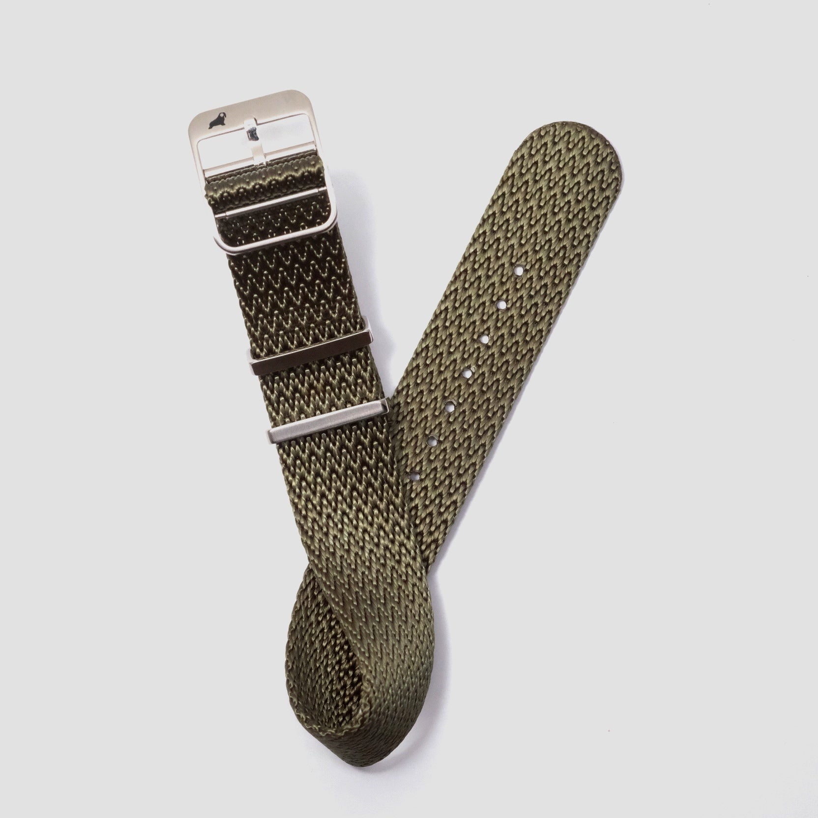 The RSM Watch Strap Herringbone Twill in Olive Drab is a dark green nylon NATO band with a silver buckle and loops, featuring a textured zigzag pattern.