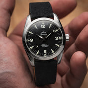 This Omega Railmaster (36mm) is a gem, fitted with the RSM basic fine canvas strap in Black Coal. The watch rests on a palm, showcasing its inverted lugs and arrow hands.