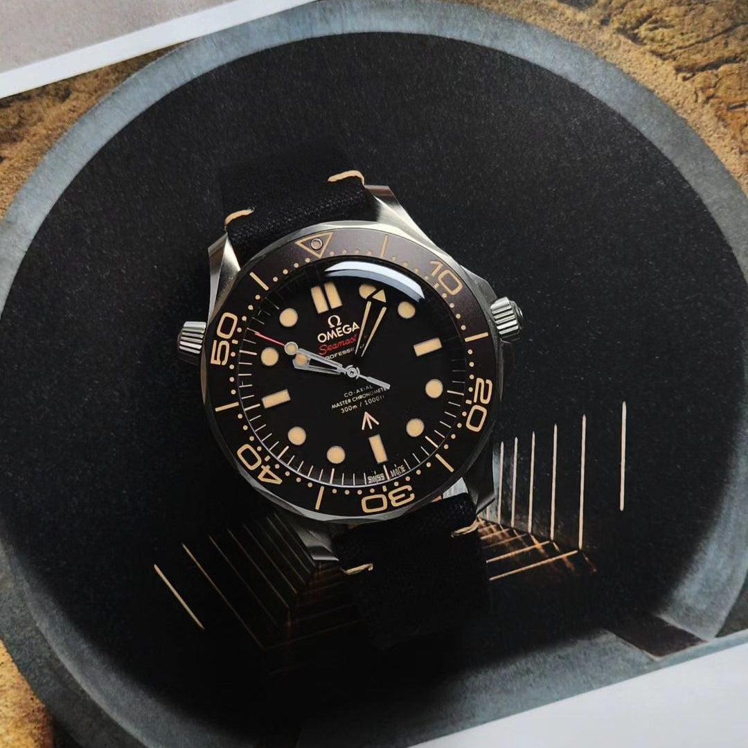 The Omega diving watch from RSM features a black fine canvas strap and a gold round face with beige luminous markers, placed in a vaulted tunnel.