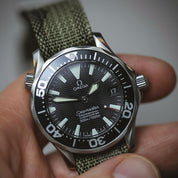 The Omega Seamaster Diver 36mm 2252.50 with wave dial and sword hands is fitted on the RSM camo strap, showcasing its smaller size.