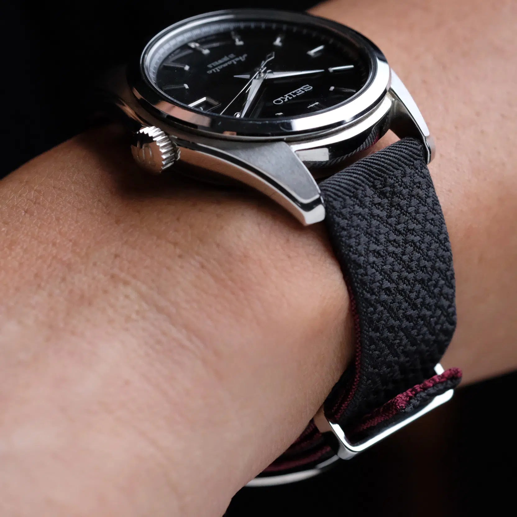 A wristwatch with a black face, silver casing, white markers, and RSM 2-Piece Silk Strap in black with burgundy lining, exuding sophistication.