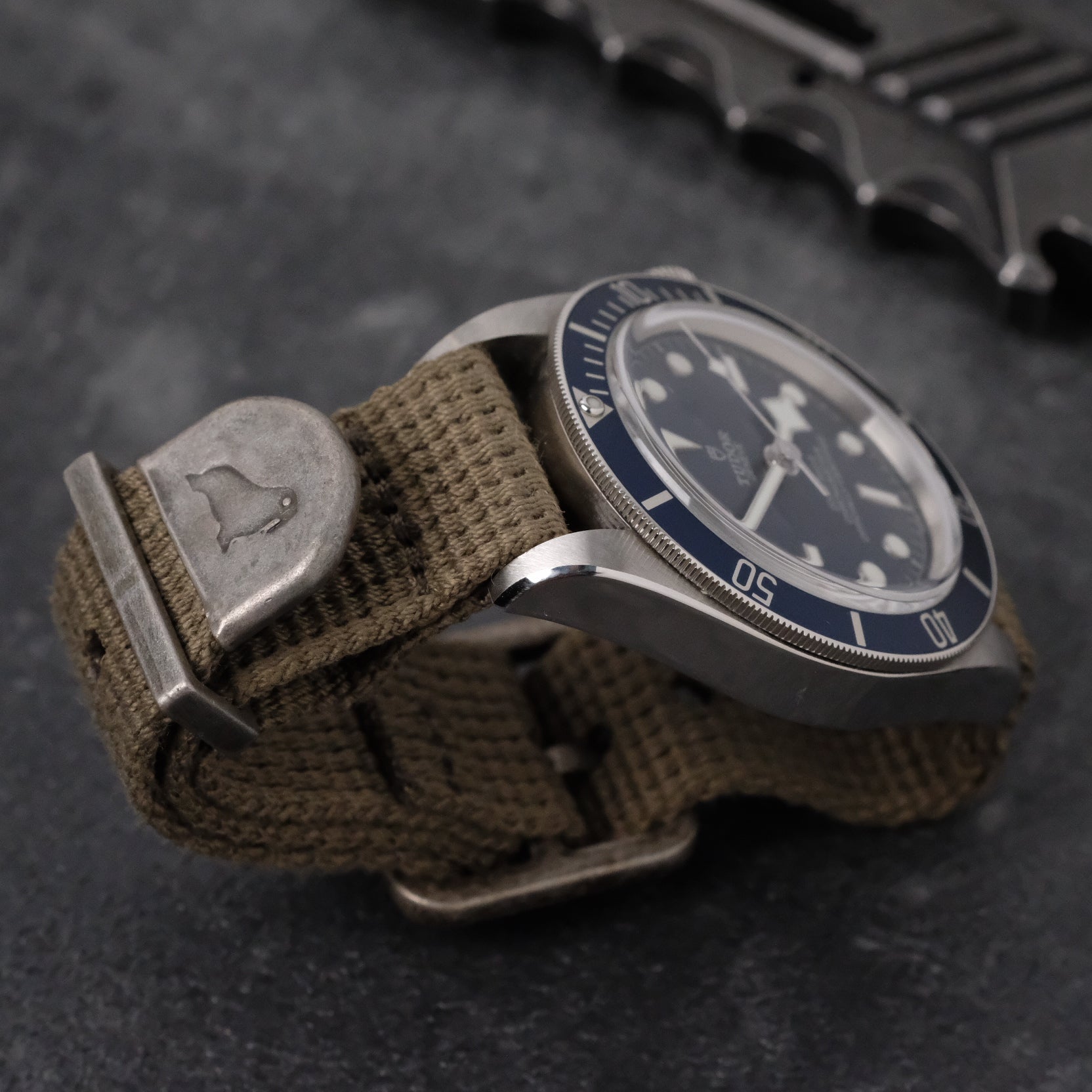 Tudor BB58 Blue with olive military watch band from RSM, featuring distressed silver end cap, keeper, and buckles for a vintage look.