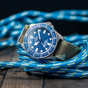 Tudor FXD Blue paired with RSM Camo Watch Strap, displayed on a wooden floor with neon blue ropes as a dynamic composition.