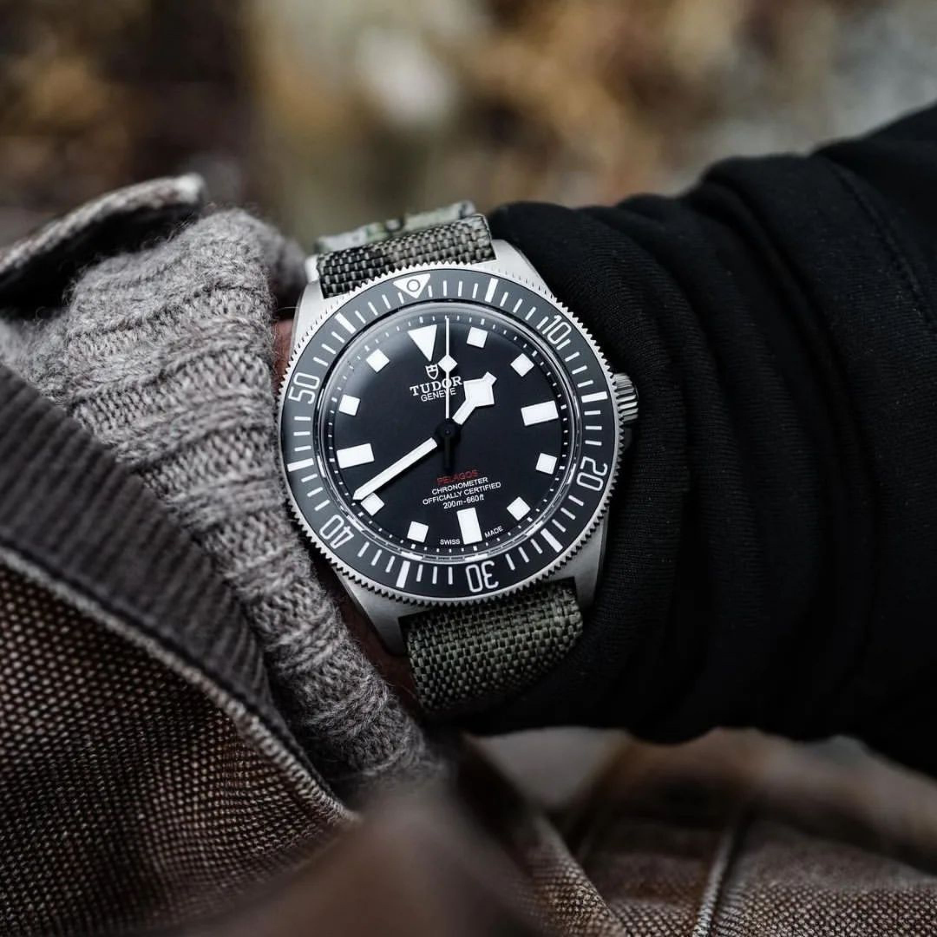 Black Tudor FXD on RSM's camo strap, worn with a winter glove, gray jumper, and canvas jacket on the wrist.