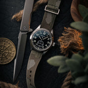 Vertex military field watch with RSM camo Zulu strap with distressed silver hardware. EDC rope, coin in the background.