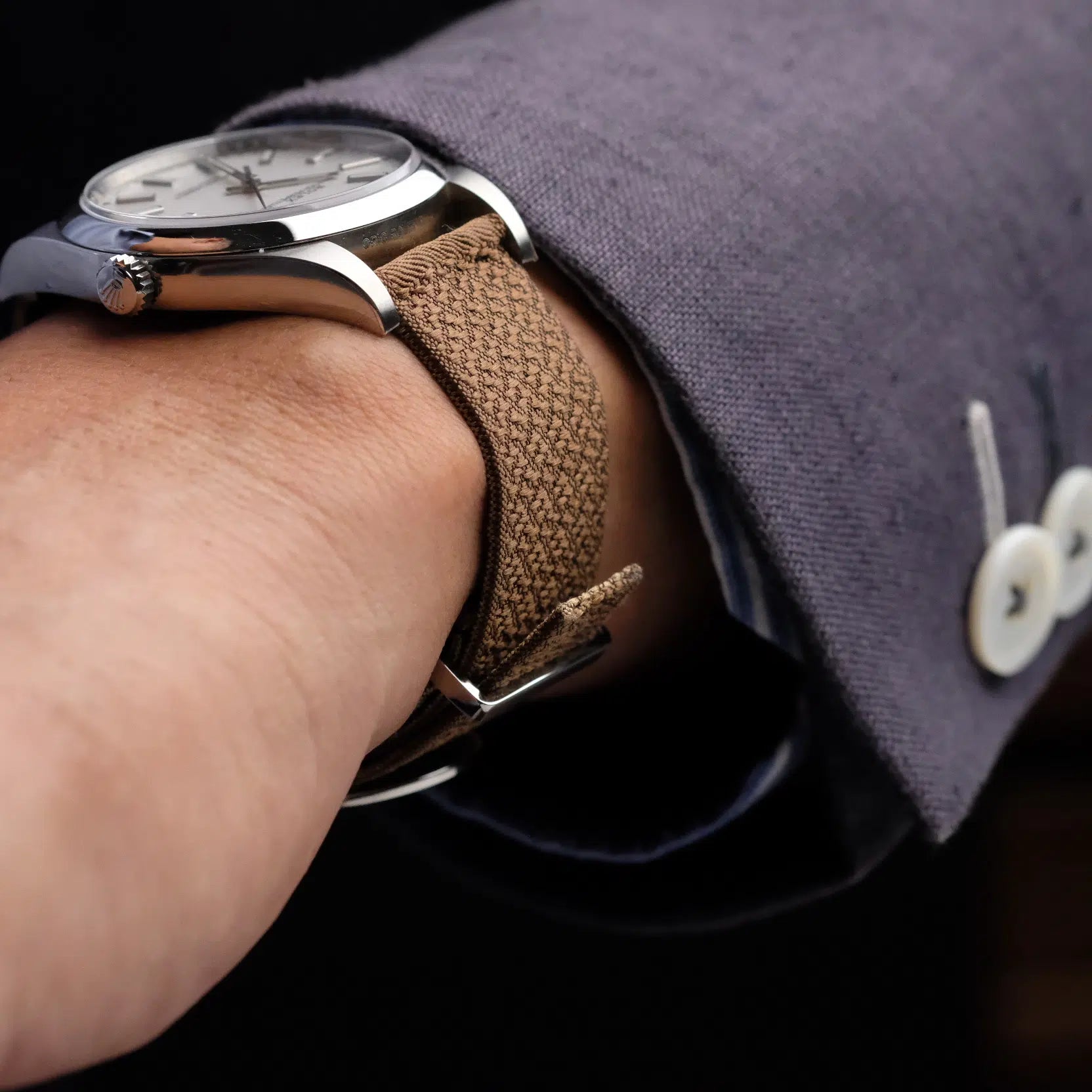 A watch paired with a Bronze 2-Piece Silk RSM Watch Strap worn by a man in a suit, exuding sophistication and style.